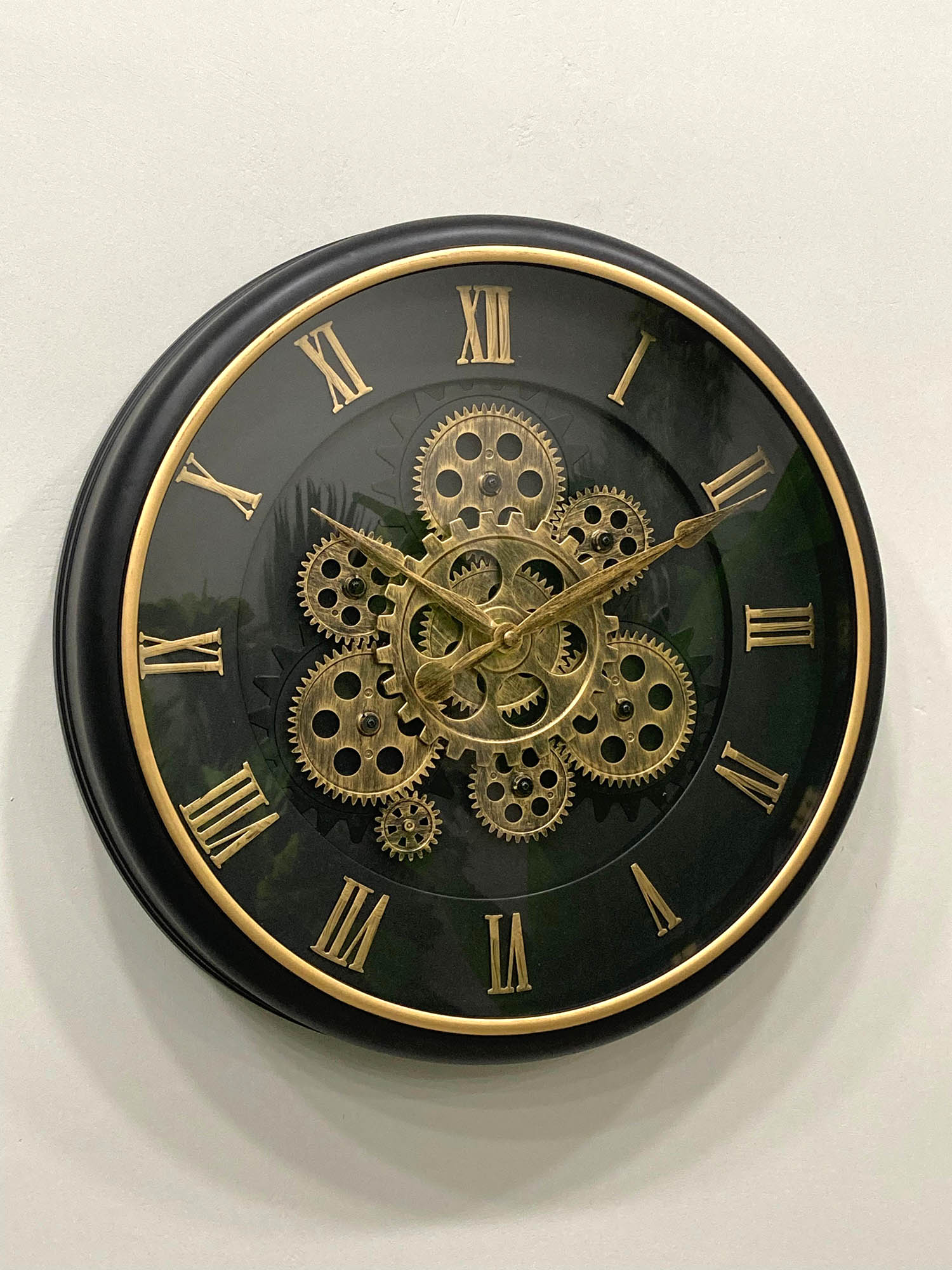 Wall clock with gold gears and Roman numerals on a black background