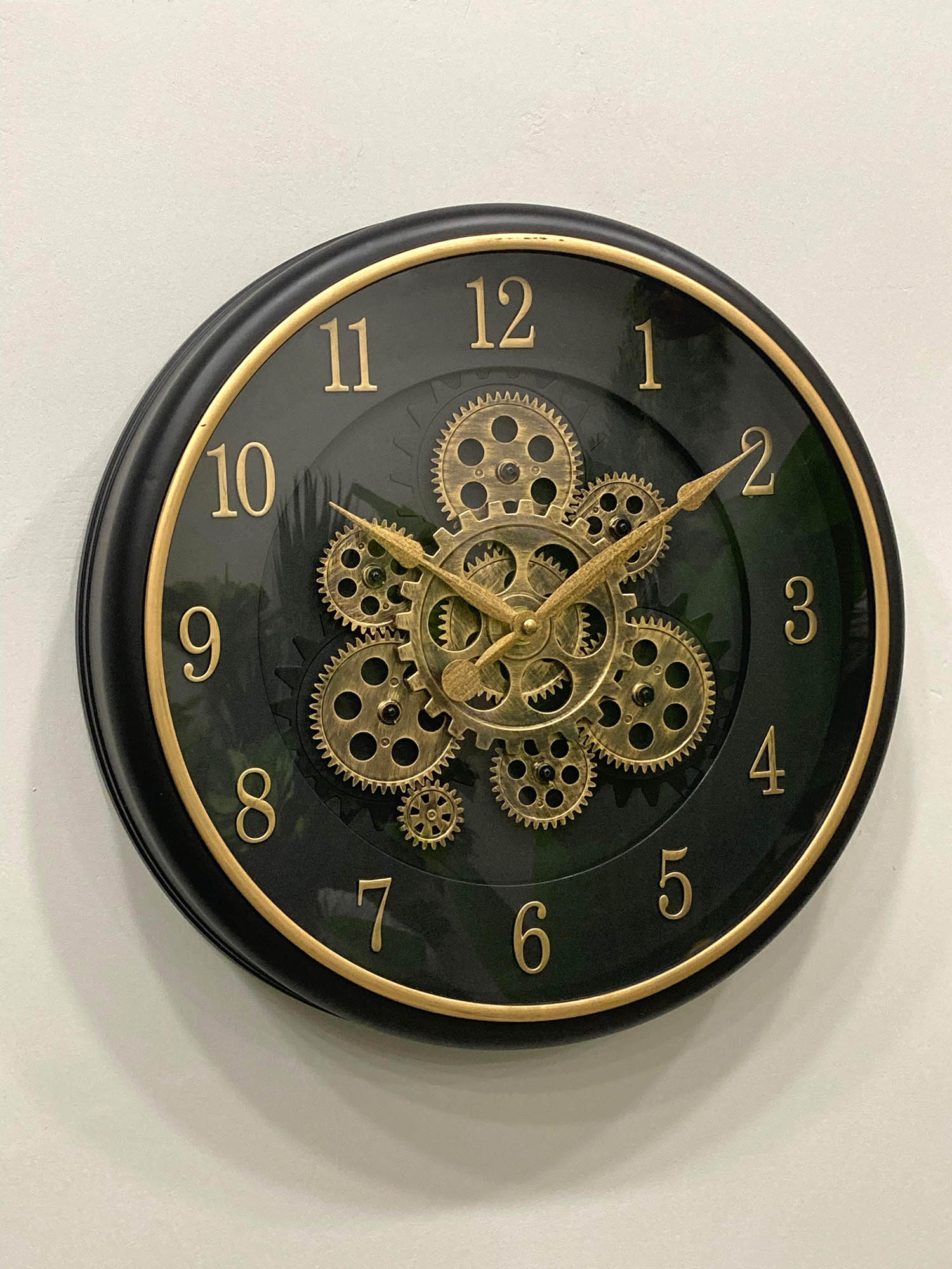Wall clock with gold gears and numbers on a black background