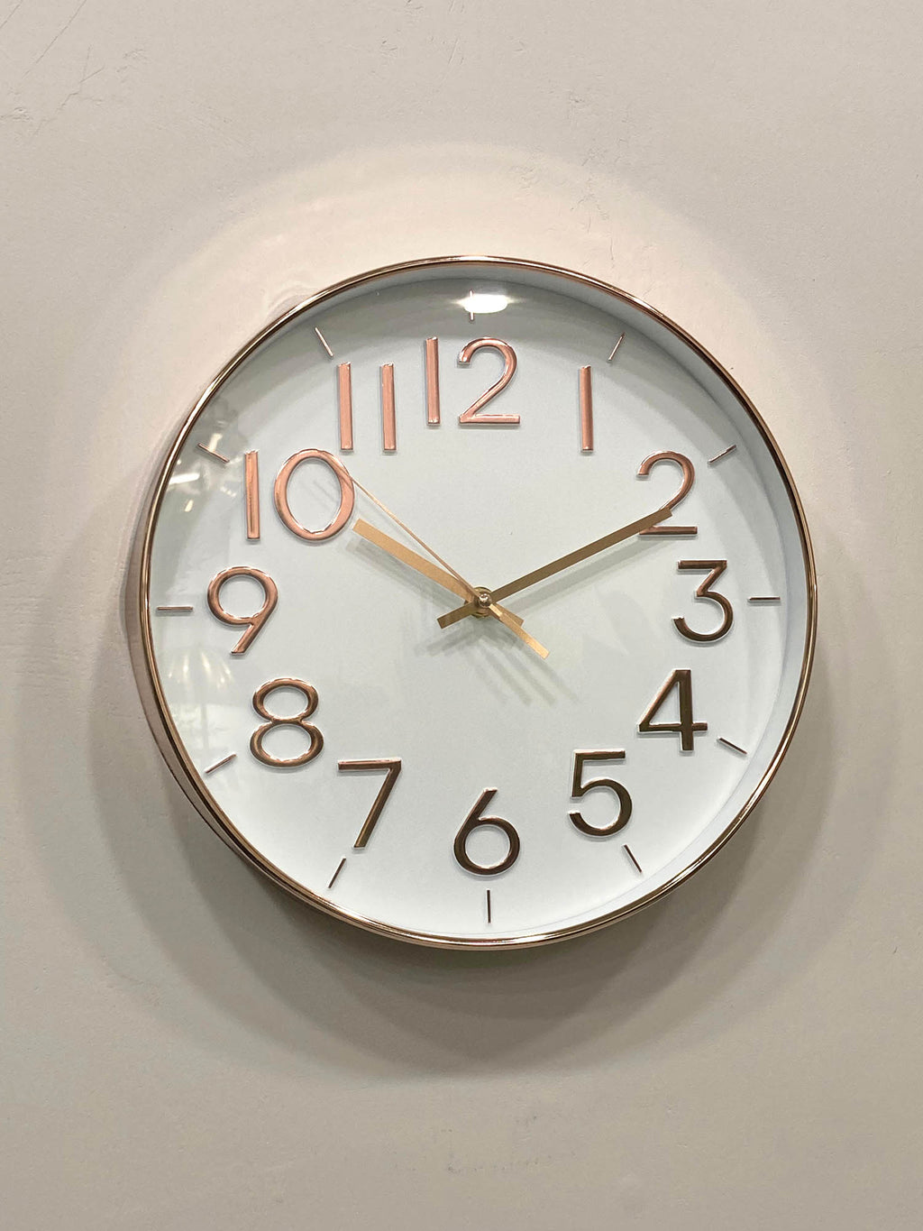 Modern wall clock for living room décor 
Round wall clock with rose gold frame and numbers on a light gray background