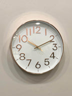Modern wall clock for living room décor 
Round wall clock with rose gold frame and numbers on a light gray background