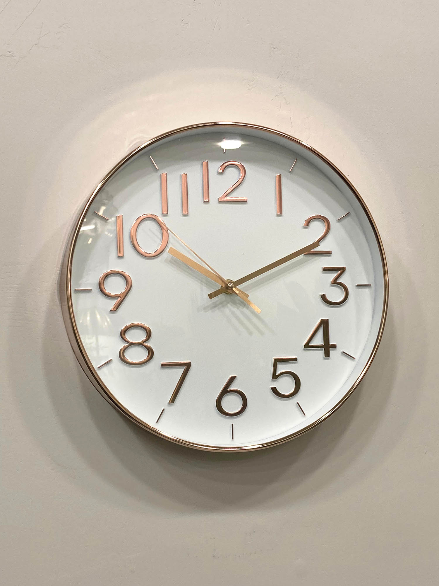 Modern wall clock for living room décor 
Round wall clock with rose gold frame and numbers on a light gray background