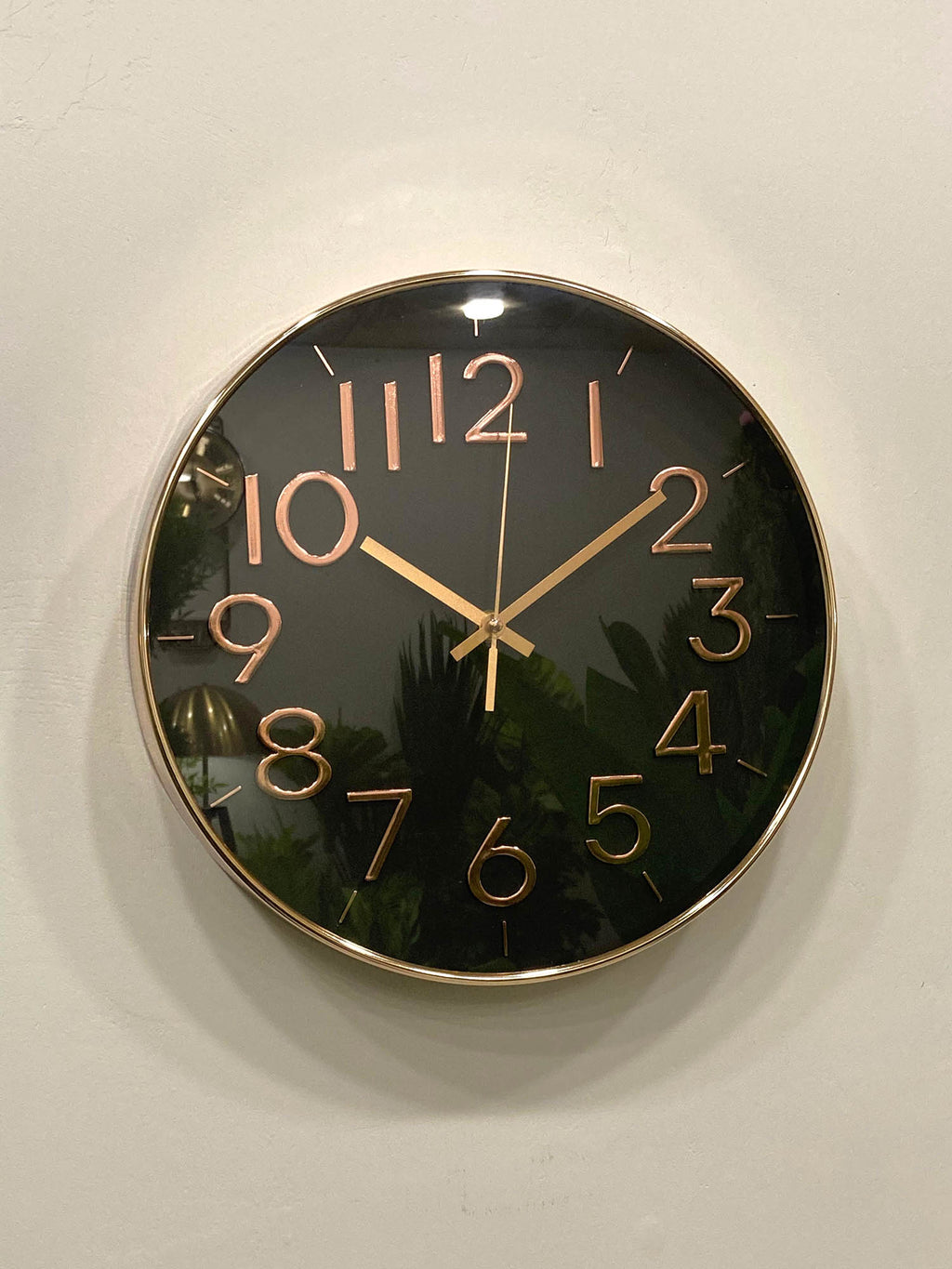 Modern wall clock for living room décor 
Wall clock with black face and gold numbers and hands on a light background