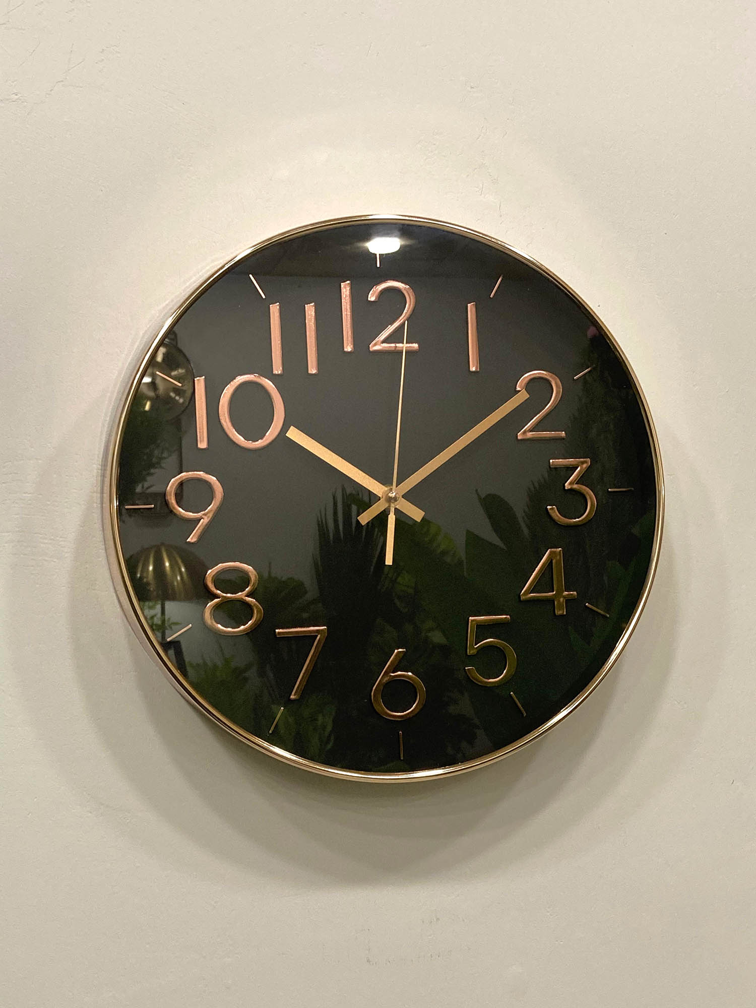 Modern wall clock for living room décor 
Wall clock with black face and gold numbers and hands on a light background