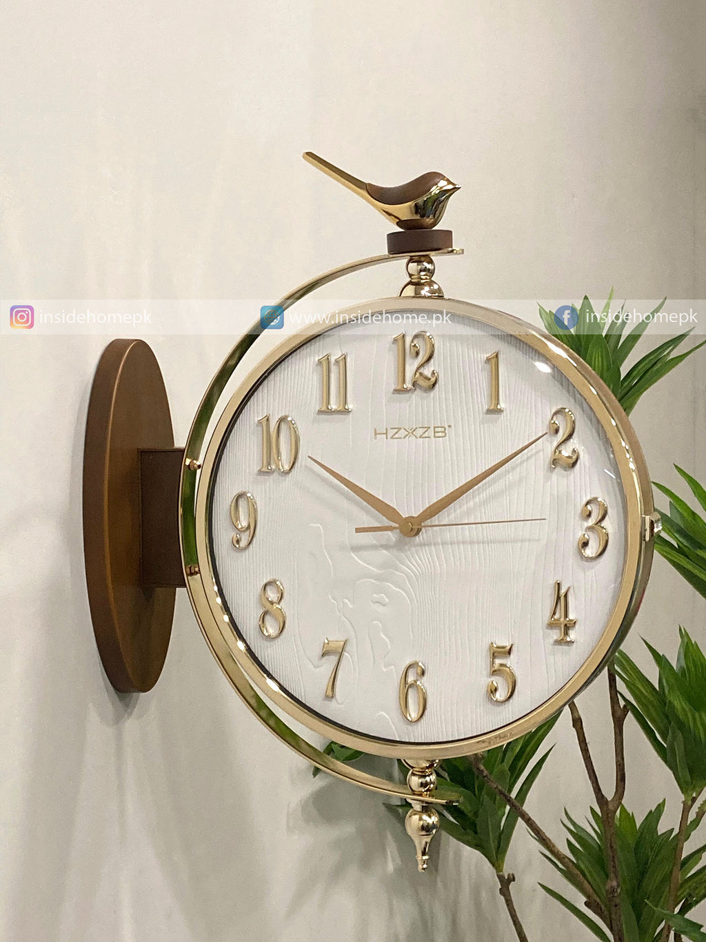 Decorative wall clock with bird design on a white wall.