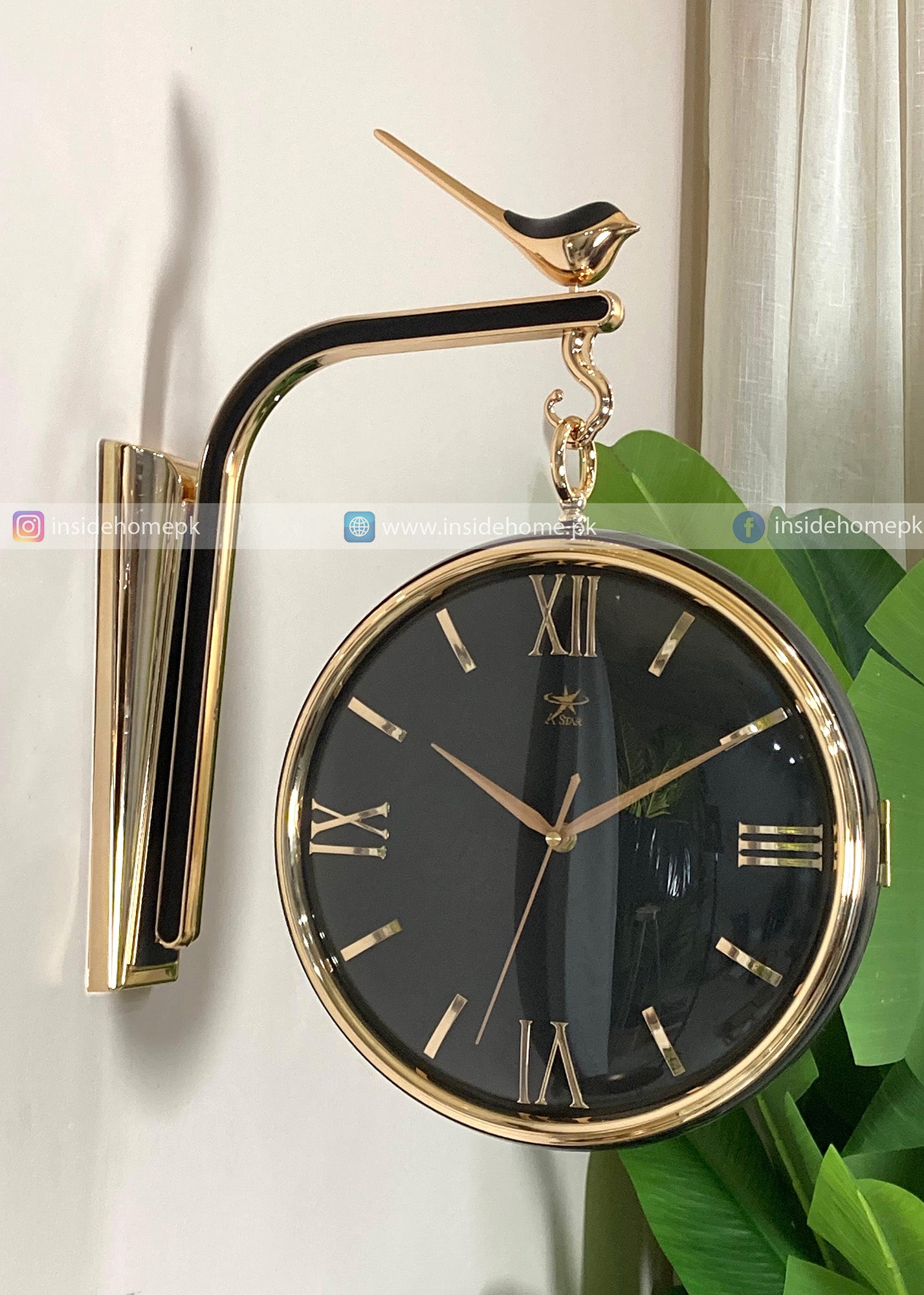 Decorative wall clock with gold bird design on a white wall.