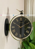 Decorative wall clock with black face and gold accents on a white wall.