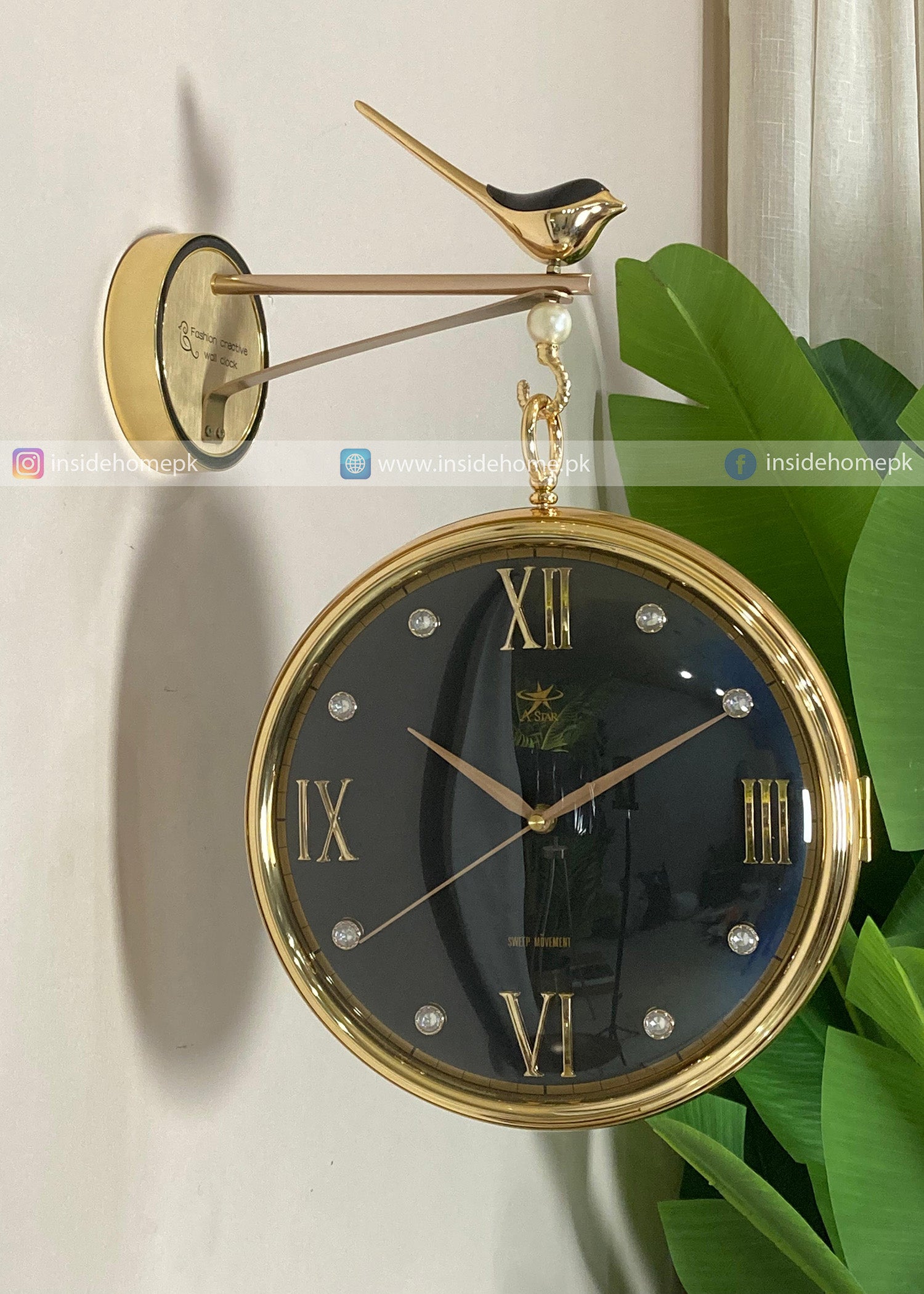 Decorative wall clock with gold frame and bird design on a white wall.