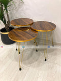 Three wooden side tables with gold metal legs on a light wood floor.