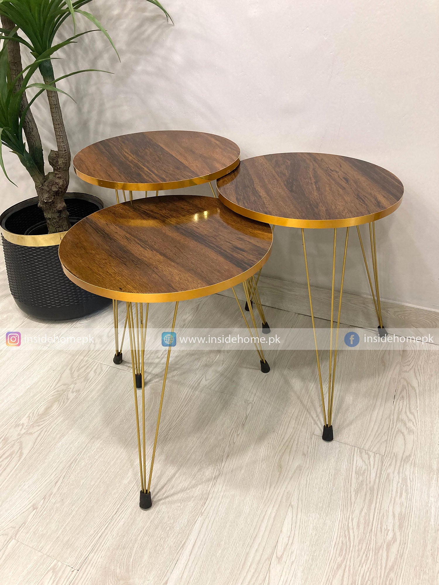 Three wooden side tables with gold metal legs on a light wood floor.