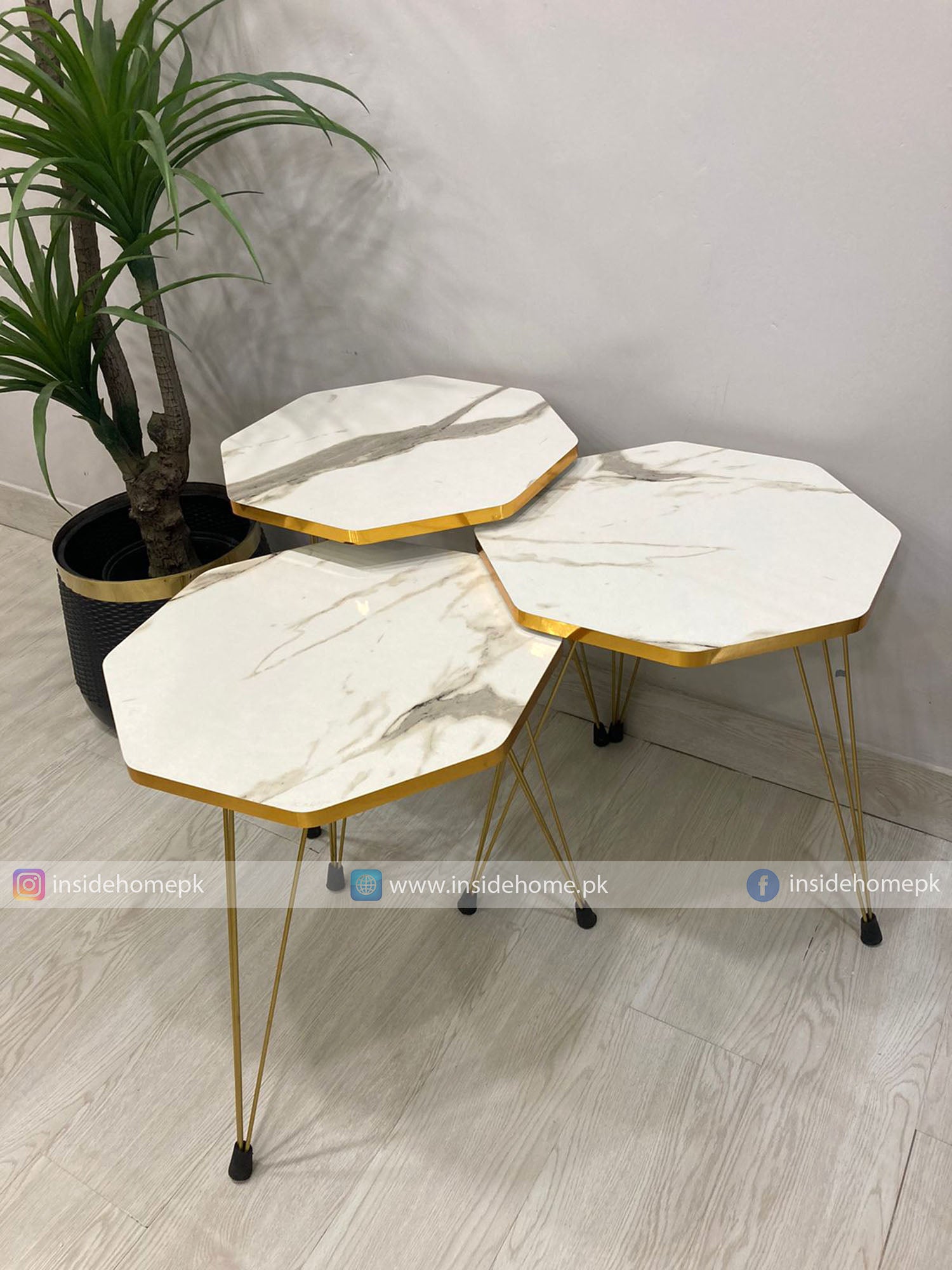 Hexagonal marble coffee tables with gold frames on a light wooden floor.