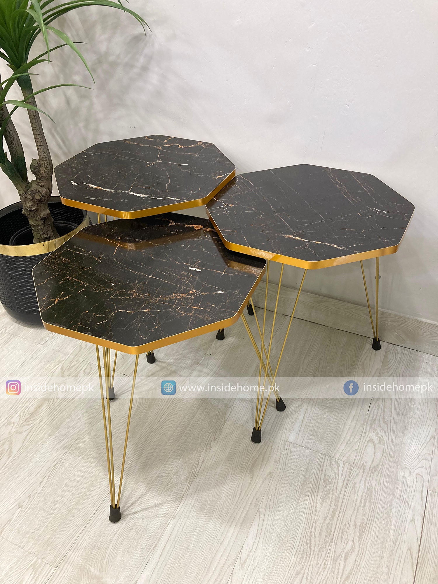 Set of three hexagonal marble-top tables with gold legs on a light wooden floor.