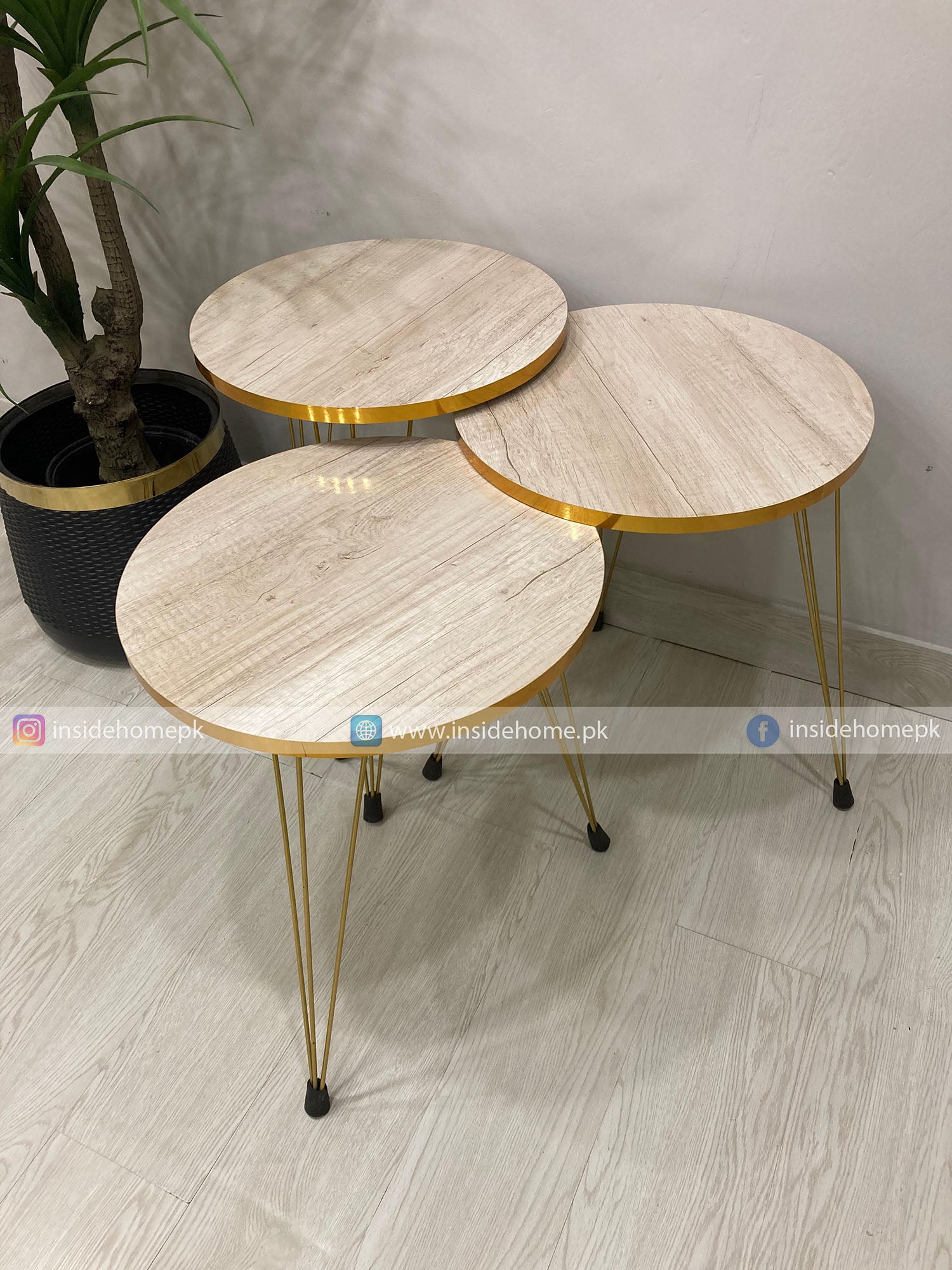 Set of three round marble top tables with gold metal legs on a light wooden floor.