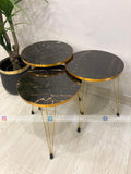 Set of three round marble tables with gold edges on a light wooden floor.