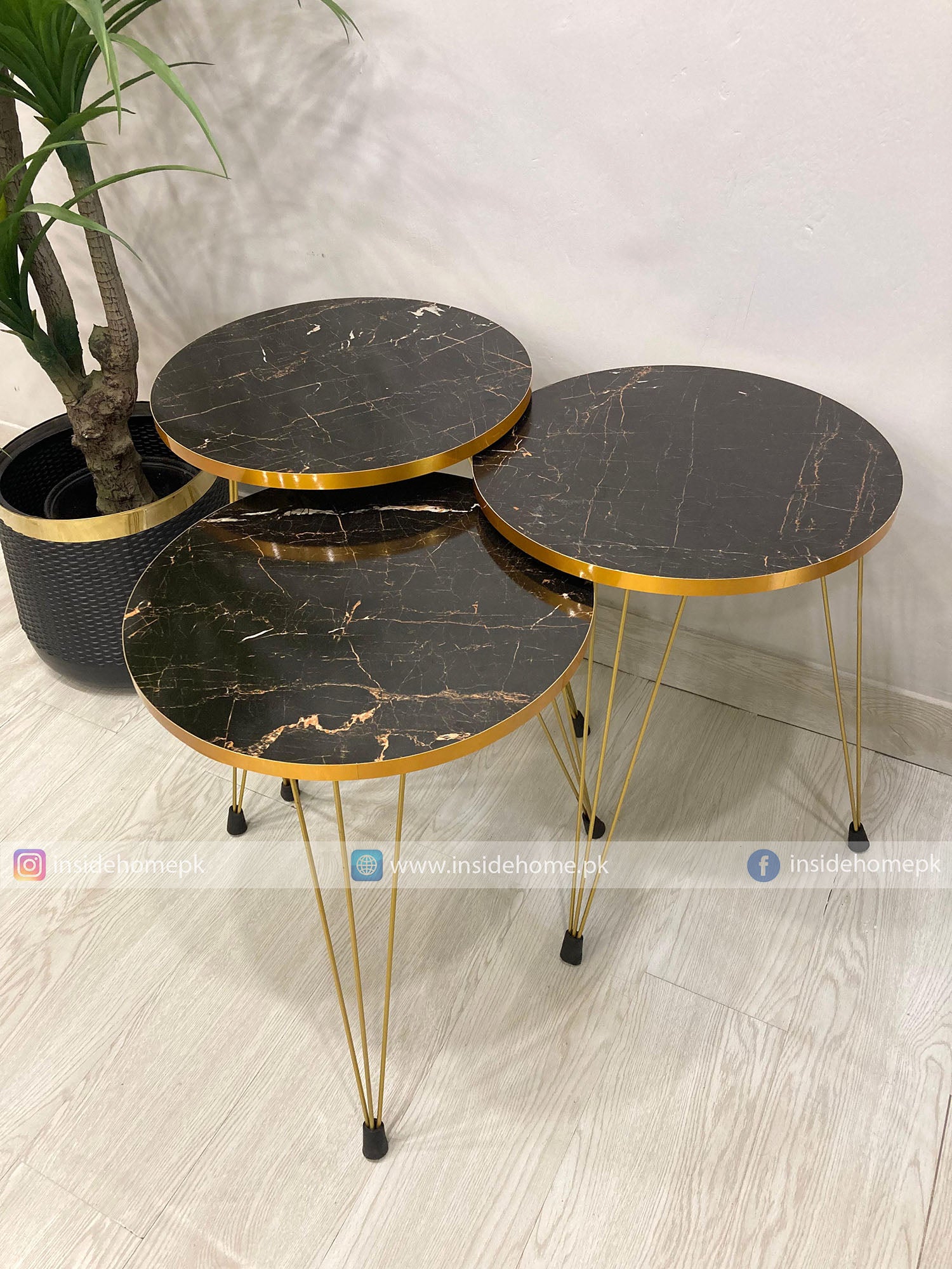 Set of three round marble tables with gold edges on a light wooden floor.